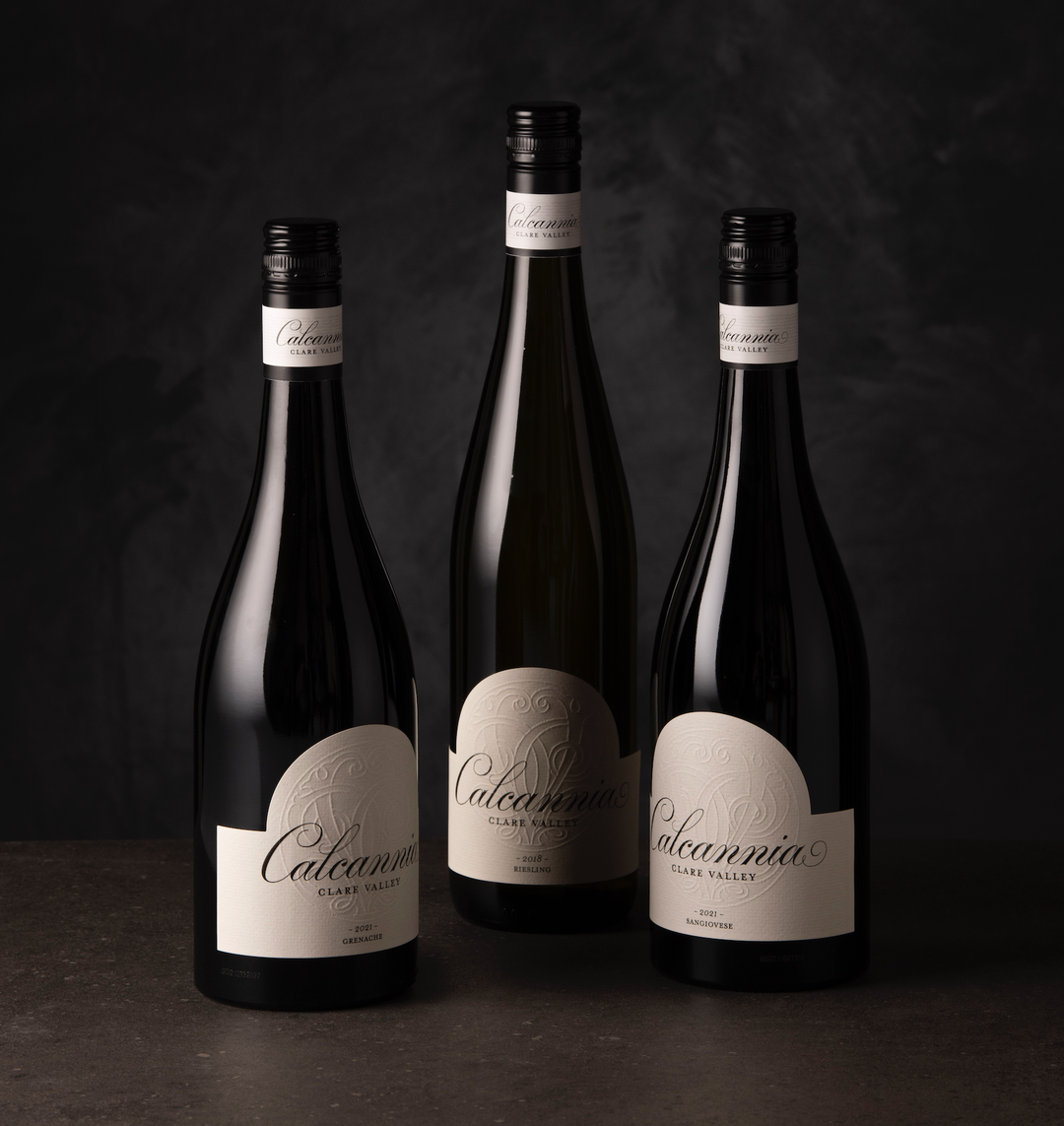 Calcannia wine bottle resting next to grapes