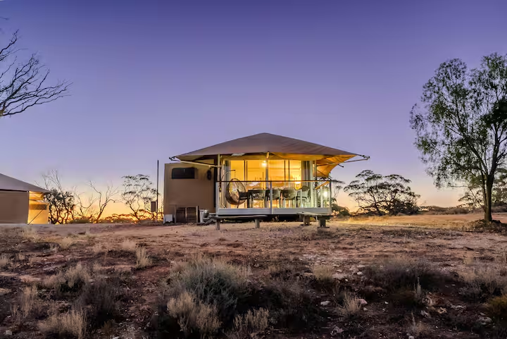 An eco-suite with a covered deck, lit from inside at sunset