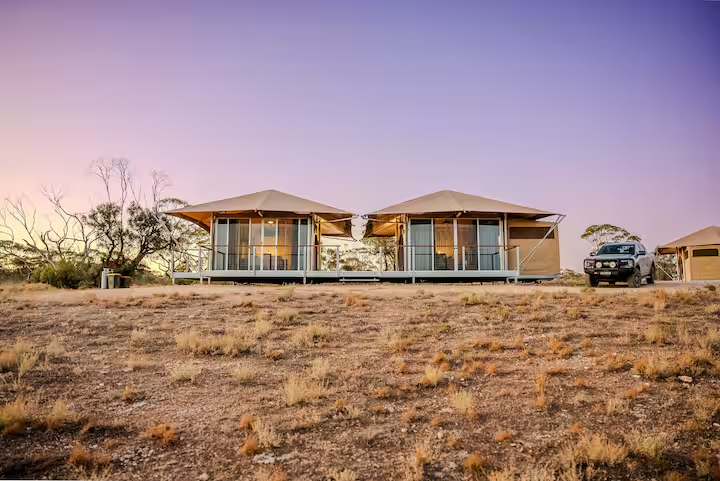 Two eco-suites side by side on open land at dusk